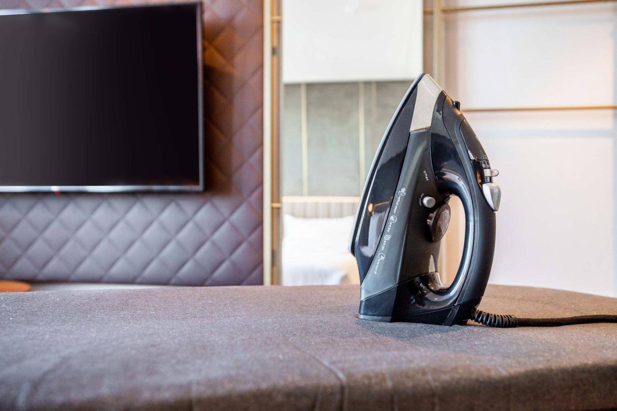 Hotel Nh Collection Copenhague Exterior foto The photo shows a black iron placed on a grey ironing board, which is covered with a fabric surface. In the background, there's a large television mounted on the wall, and the setting appears to be a modern room with stylish decor, featuring a quilte