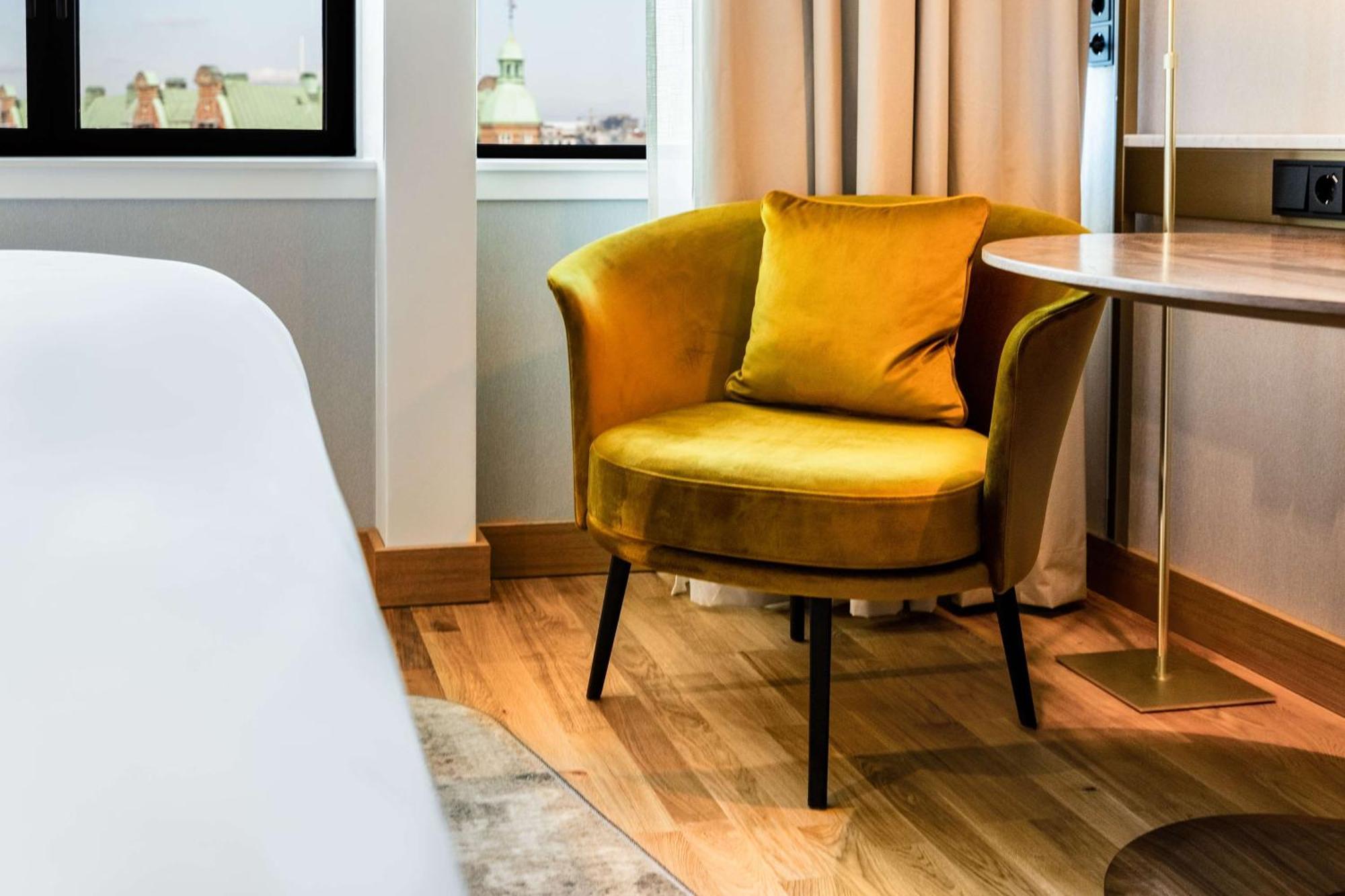 Hotel Nh Collection Copenhague Exterior foto The photo shows a stylish interior space featuring a modern, round yellow armchair with a plush cushion, placed next to a small table. The chair has a contemporary design with slender legs. In the background, there are large windows with light curtai